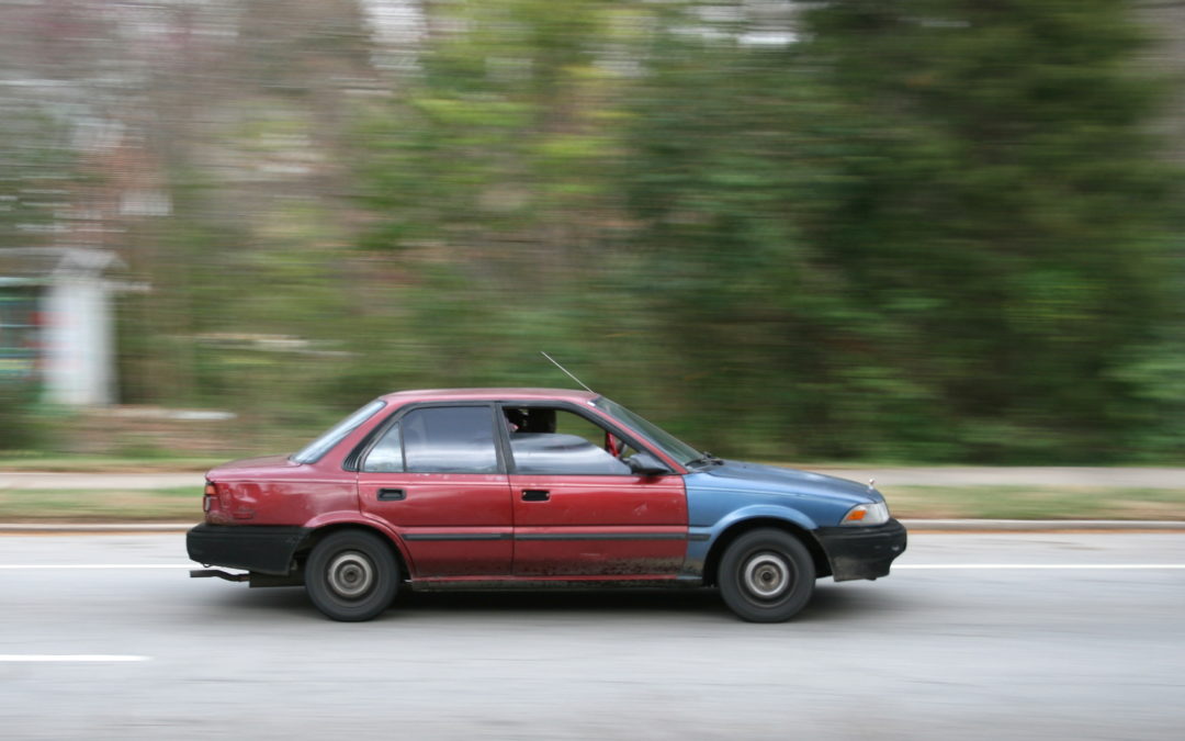 Beat Up Car driving on the highway.