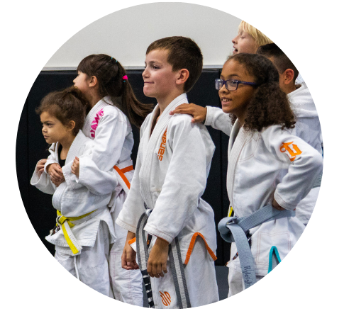 3 young girls standing together in jiu-jitsu uniforms