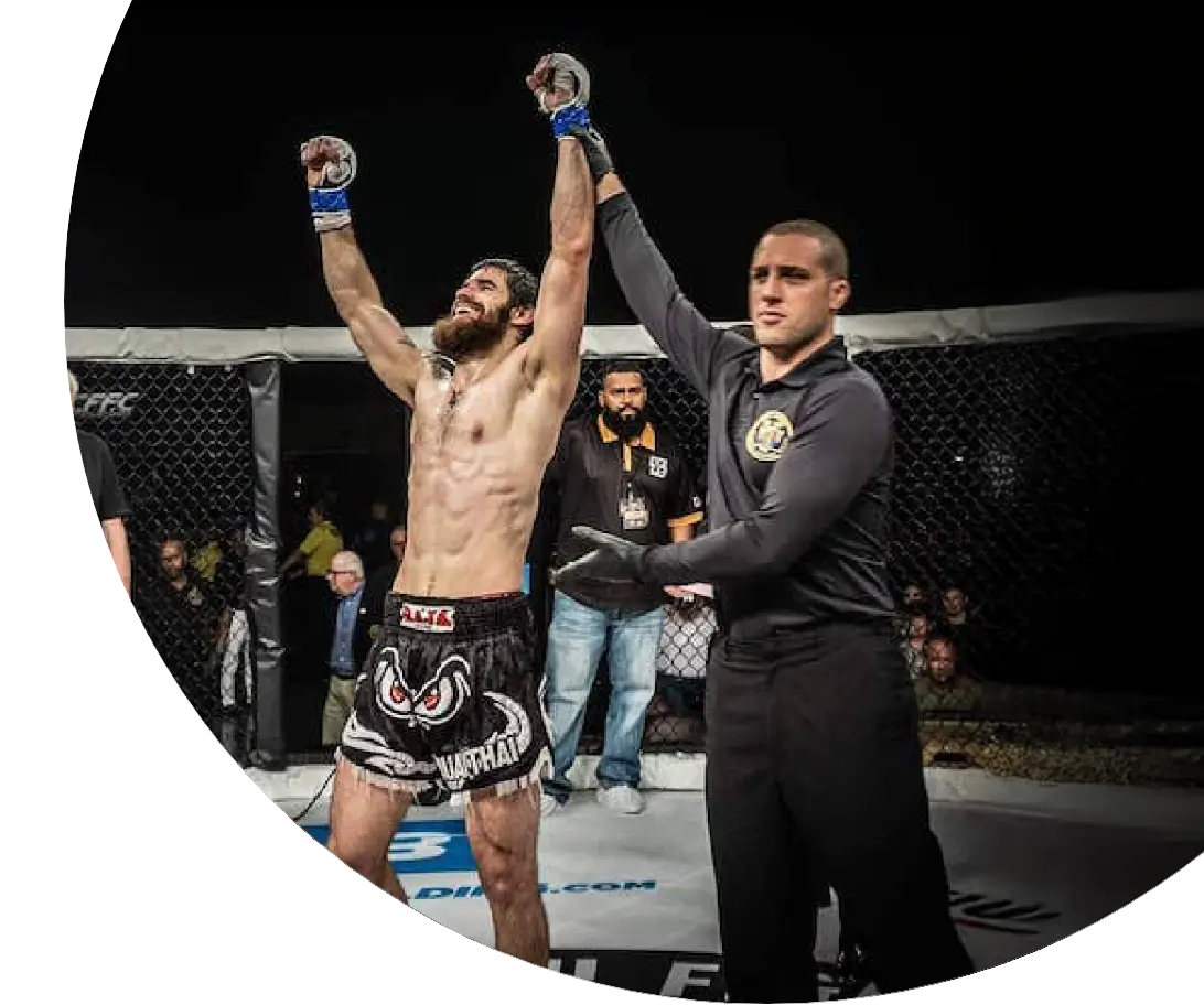 The winner of a MMA match raises his arms triumphantly at the end